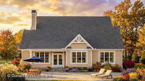 House Plan with a gray roof and beige exterior, surrounded by autumn trees and a sunset sky.