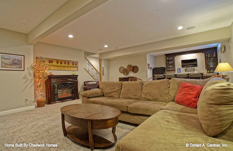 Couch seating with fireplace in the entertainment room. The Beauxville plan 1236.