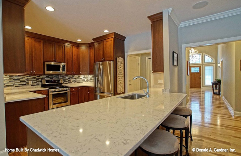 Kitchen island with a sink and bar seating. The Beauxville plan 1236.