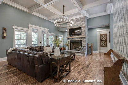 Great room with fancy coffered ceiling, crown molding, a large fireplace with hearth and plenty of doors out to the back porch