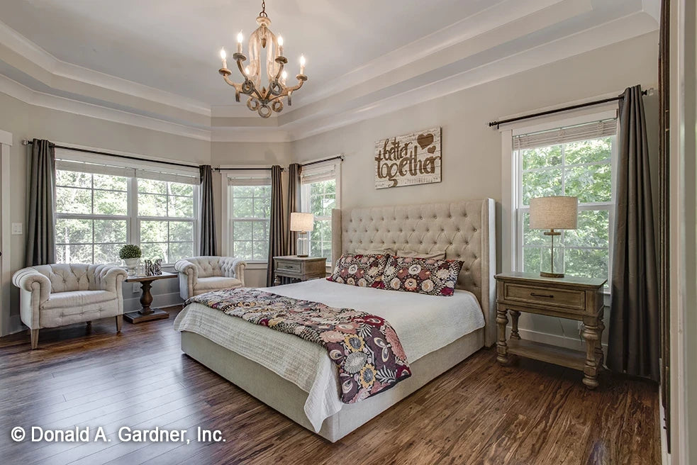 Spacious master bedroom with sitting area and lots of windows, a tray ceiling with crown molding