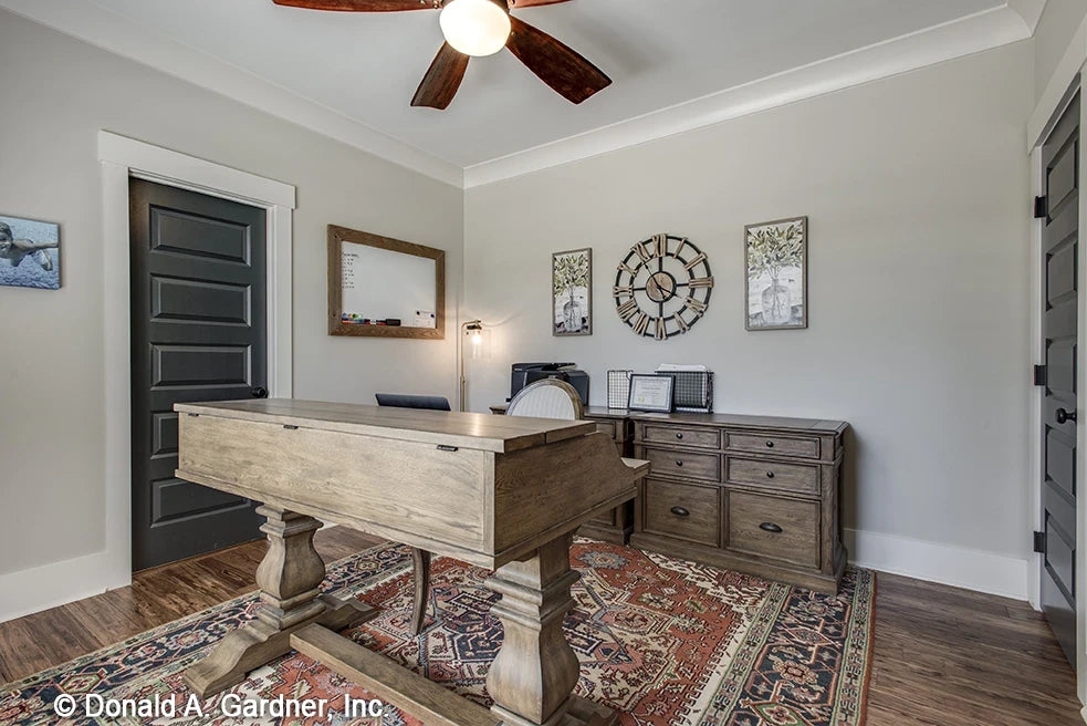 Office room with crown molding, hard wood floors and unique desk.