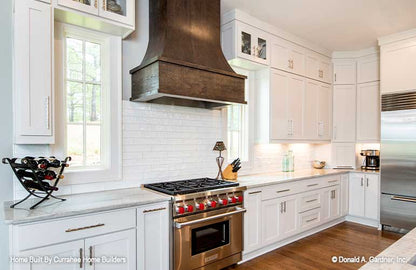 Subway tile backsplash and wood like vent above the stove in the kitchen. The Chatsworth plan 1301.