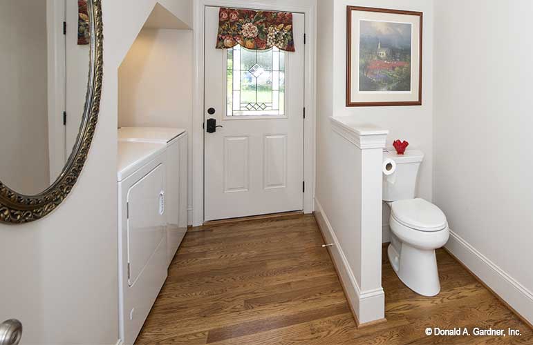 Entry way door into the laundry area and toilet off to the side with half wall. The Cline plan 1419