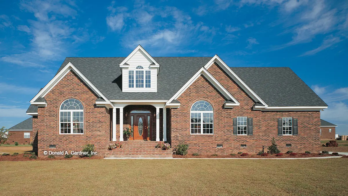 Photographs submitted by the customer. Front view photograph of a brick home with gables. The Emory plan 804.