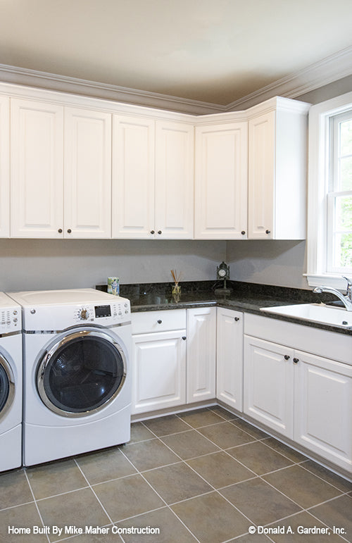 White cabinets and a sink in the utility room. The Holden plan 1168.