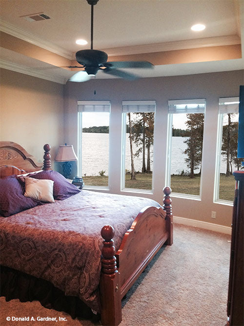 Master bedroom pictured with rear windows and view of lake for house plan 1319 The Lucerne