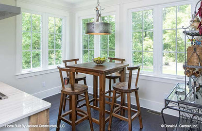 Bar height table and chairs in the breakfast nook, surrounded by windows. Lucinda plan 1514