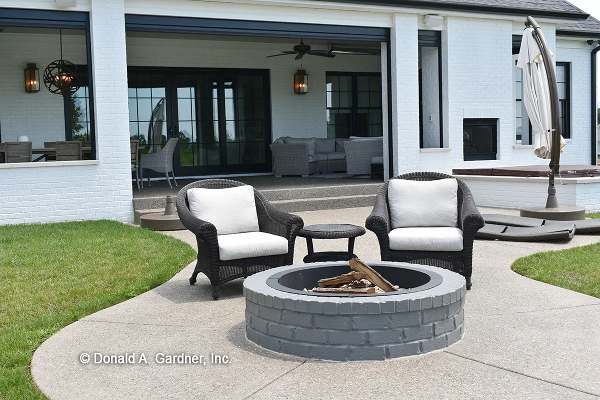 A firepit extends outdoor living to the patio of one story house plan 1378 The Roseburg