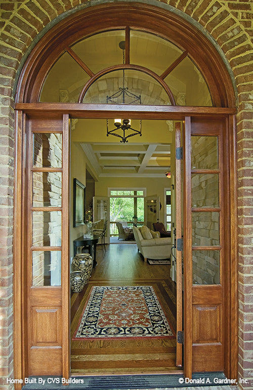 Exterior view of the foyer with the door open and an arched window above. Elegant arched ceilings and beams in the foyer. The Runnymeade plan 1164.