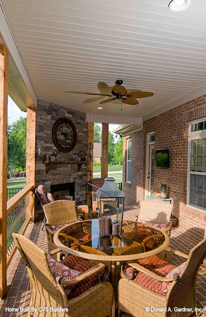 Covered rear porch with stone fireplace and outdoor ceiling fan. The Runnymeade plan 1164.