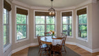 Breakfast nook area is surrounded by windows and features crown moulding.