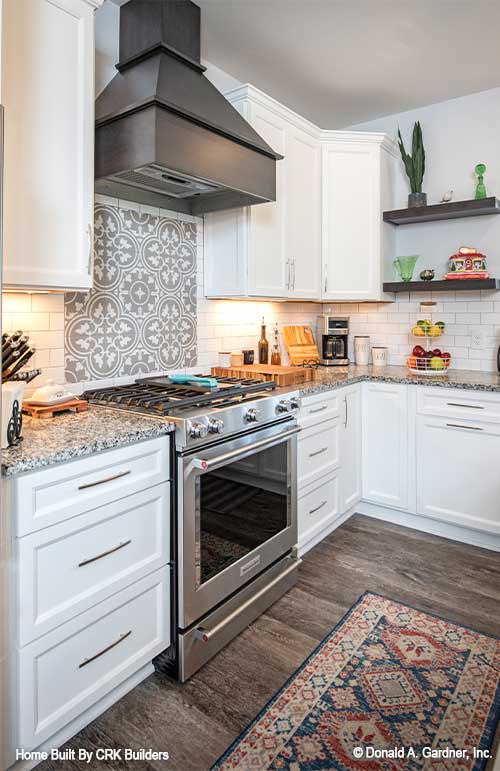 Tiled backsplash over the stainless-steel gas stove. Sloan plan 1528