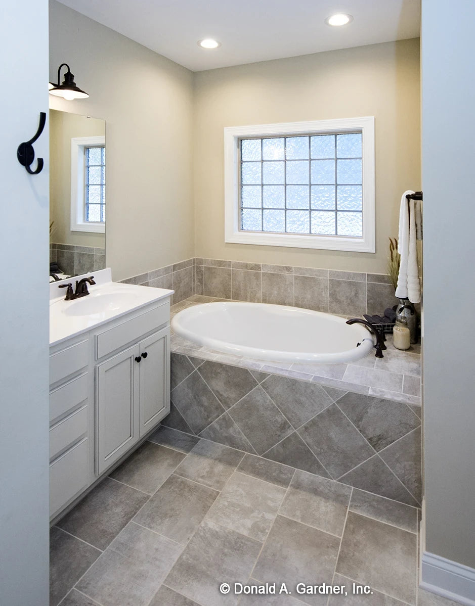 Master bathroom has a large soaking tub with a glass block window for natural light