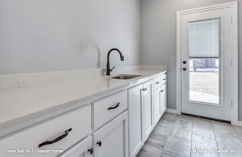 Exterior door to enter the utility room with sink and lower cabinets. Thurman plan 1515