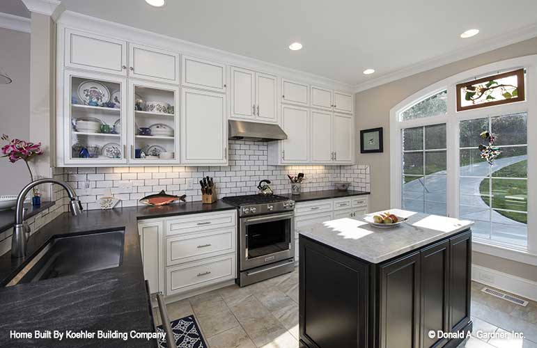 Arched window and white cabinets in the kitchen. The Tristan plan 1311.