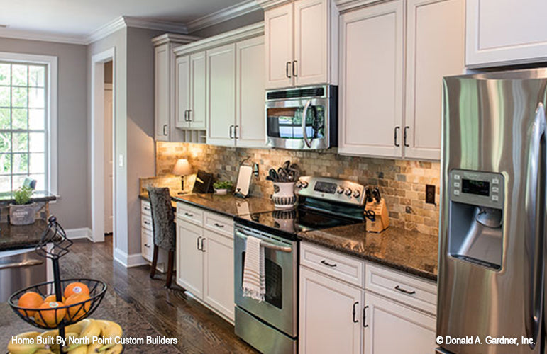 White cabinets and stain-less steel appliances in the kitchen. The Weatherford plan 1053.