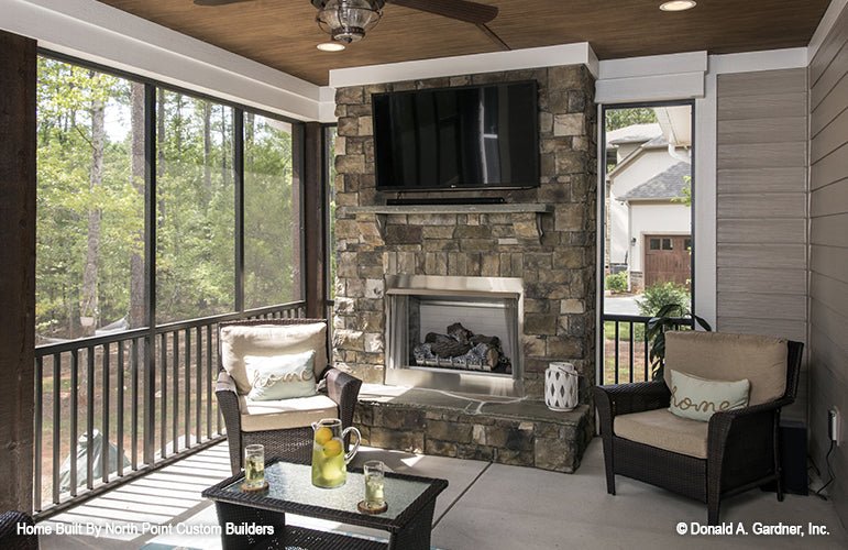 Stone fireplace with tv above in the screened in porch. The Wilkerson plan 1296.