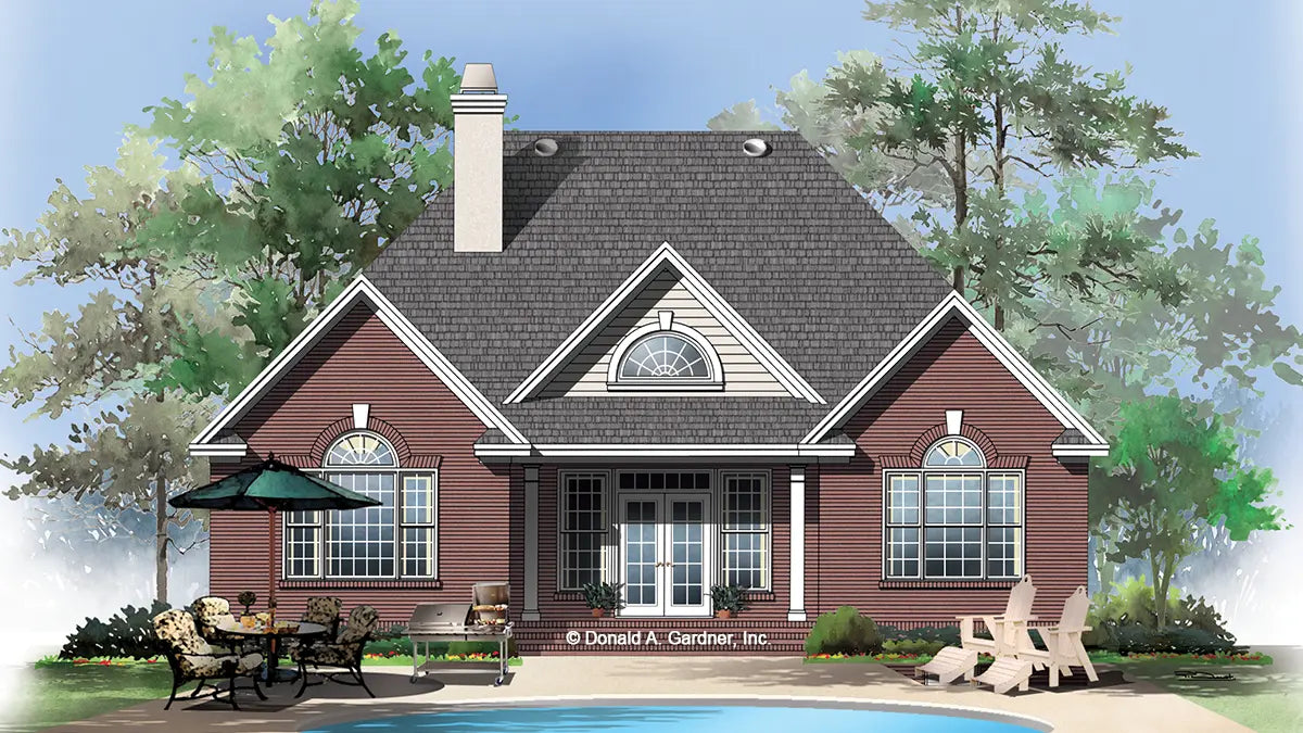 rear of the house has red brick siding, a covered porch, a chimney, and arched topped windows