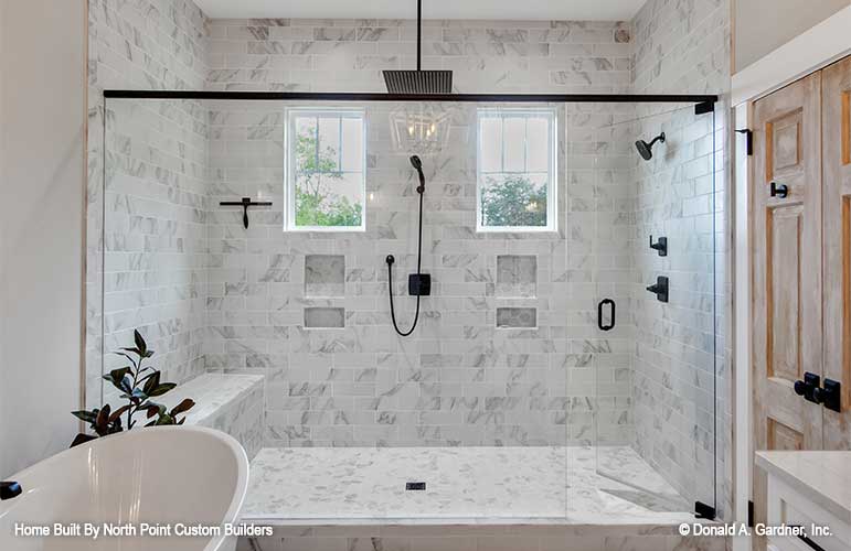 Tiled walk-in shower with a bench in the master bathroom. The Zander plan 1478.